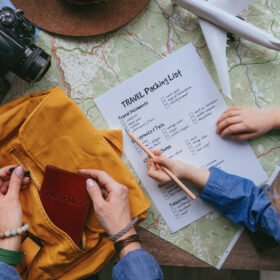 ☀️ Travelicious Packing List for a Sunny Holiday Family preparing for travel. Travel essentials on the wooden background. Little girl checking travel packing list while he…