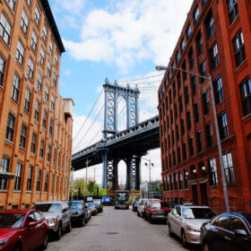Manhattan bridge seen from a red brick buildings in Brooklyn street in perspective, New York, USA. Beautiful classic apartments in New York City. Beautiful american street. Famous view.