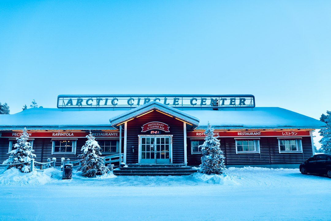 Snow-covered Arctic Circle Center building and restaurant surrounded by pine trees in winter.